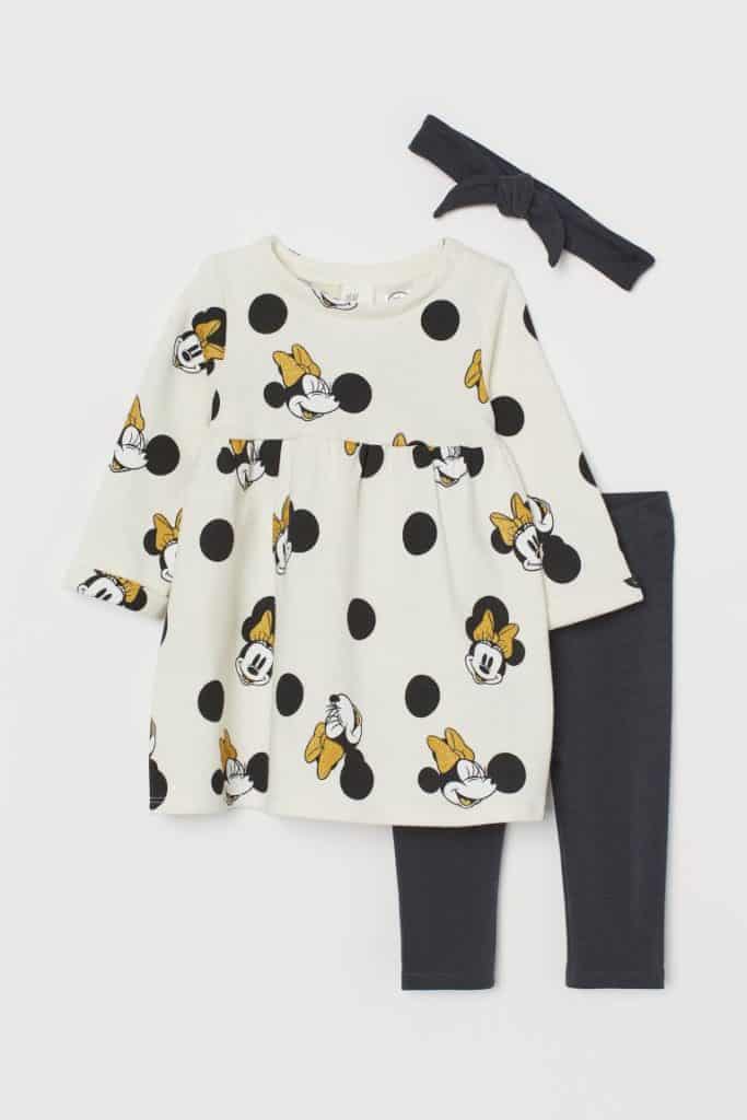 Get your little Disney fan ready for an enchanting day at the parks with this magical outfit featuring a Minnie Mouse dress, classic black leggings, and a coordinating black headband displayed on a white background. Inspired by H&M’s beloved kids’ collections, this charming ensemble channels the fun and whimsy of Disney parks—perfect for family trips to Disneyland or Walt Disney World.