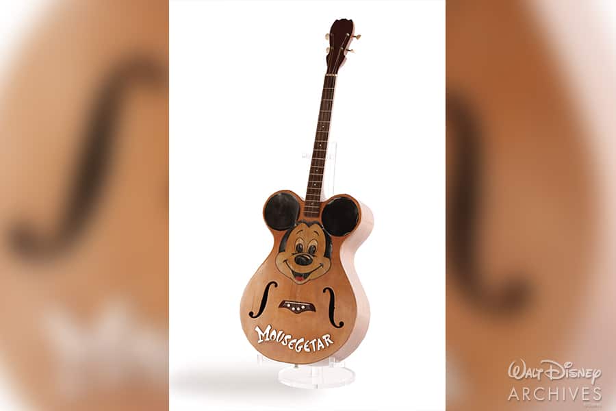 Limited edition "Mousegetar" acoustic guitar featuring the iconic Mickey Mouse face and ears, commemorating 65 years of the Mickey Mouse Club, displayed on a crisp white backdrop—perfect for Disney fans and collectors.