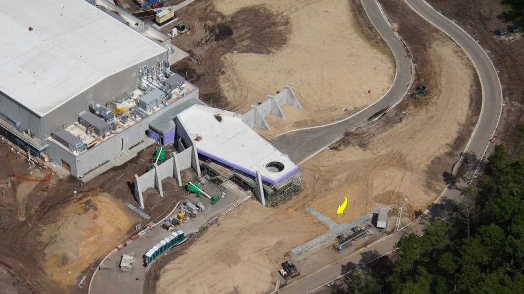 Aerial view of Walt Disney World construction highlights an upcoming attraction, featuring a massive show building, winding access road, and numerous construction vehicles as the magic takes shape.