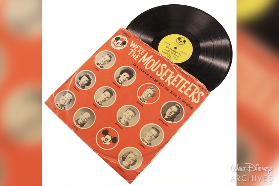 Commemorative "We're the Mouseketeers" Disney record celebrates 65 years of the Mickey Mouse Club, featuring iconic Mouseketeers photos on a bold orange cover, partially showing outside its sleeve—a nostalgic collectible for fans of classic Disney entertainment.