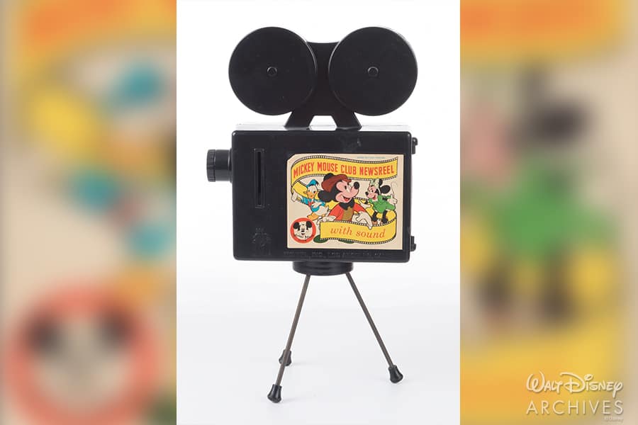 Celebrate 65 years of Disney magic with this retro-style Mickey Mouse Club Newsreel toy camera, styled in classic black and set on tripod legs—perfect for Disney fans and collectors looking to capture the nostalgia of the theme park experience.