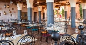 Spice Road Table at EPCOT features an inviting open-air dining area with rows of colorful chairs, vibrant lanterns hanging overhead, and plenty of empty tables—perfect for taking a break and enjoying Mediterranean flavors during your visit to the park.