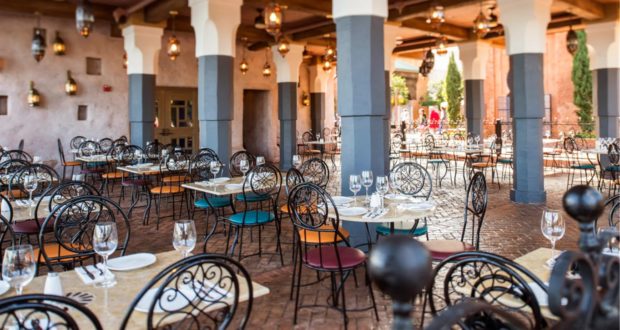 Spice Road Table at EPCOT features an inviting open-air dining area with rows of colorful chairs, vibrant lanterns hanging overhead, and plenty of empty tables—perfect for taking a break and enjoying Mediterranean flavors during your visit to the park.