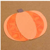Whimsical paper pumpkin craft featuring vibrant orange oval shapes and a small purple stem, set against a brown background—an enchanting Princess-inspired decoration ideal for Thanksgiving celebrations at your favorite theme park.