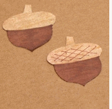 Two brown acorns with tan tops, styled like royal crowns, sit on a light brown background—ideal for enhancing your theme park event invitations or princess-themed show signage with a festive Thanksgiving twist.