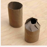 Two empty toilet paper rolls, one with its end folded inward, sit on a light brown surface—ideal for crafting your own Disney-inspired Thanksgiving table decorations to bring a bit of that theme park magic home.