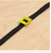 A MagicBand-inspired black strap with a yellow, Mickey-style buckle rests on pale wood, recalling Disney park adventures.