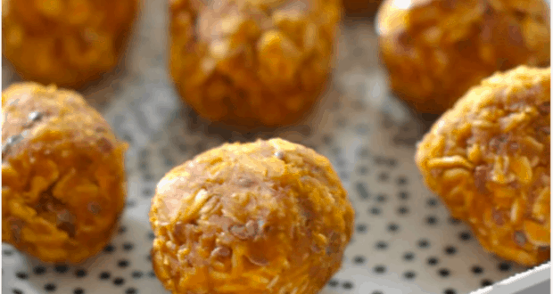A festive close-up of Pumpkin Energy Balls and oat bites, perfectly round and ready for snacking, served on a white plate with playful black dots—ideal for fueling up before your next theme park adventure or as a magical fall treat between rides.