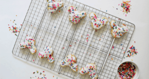 Whimsical animal-shaped cookies decorated with white icing and rainbow sprinkles rest on a cooling rack, echoing the playful spirit of theme park treats. Sprinkles scattered around evoke the festive atmosphere of a day at your favorite entertainment destination—perfect for making celebrations magical and sharing smiles like souvenirs from a memorable adventure.