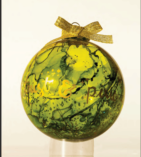 A vibrant green and yellow marbled ornament with elegant gold lettering and a shimmering gold bow on top, showcased on a transparent stand. This Mickey-inspired decoration is an enchanting collectible for Disney Parks fans and anyone inspired by magical DIY creations from Walt Disney World.