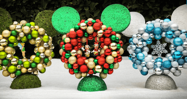 Festive Mickey Mouse-shaped wreaths crafted from colorful ornaments are arranged on a blanket of snow, capturing the magic of Disney Parks during the holidays—perfect inspiration for fans looking to bring a bit of that enchanted seasonal decor home.