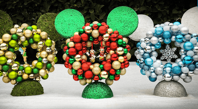 Festive Mickey Mouse-shaped wreaths crafted from colorful ornaments are arranged on a blanket of snow, capturing the magic of Disney Parks during the holidays—perfect inspiration for fans looking to bring a bit of that enchanted seasonal decor home.