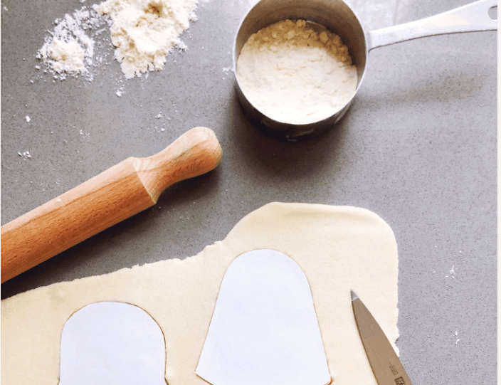 Rolling pin, flour, and Star Wars paper templates on dough with a knife set out on a countertop, ready for fans to cut out themed shapes—ideal for creating Galaxy’s Edge-inspired kitchen crafts or homemade Star Wars souvenirs.
