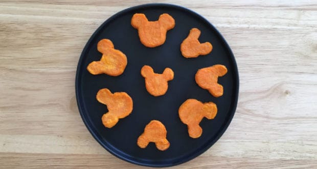 Celebrate Thanksgiving Disney style with eight Mickey-shaped sweet potato nuggets, perfectly arranged in a circle on a sleek black plate set atop rustic wood—bringing a touch of magic to your holiday feast.