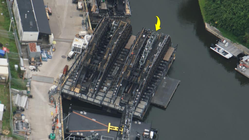 Aerial view of a canal lock system with its gate open, highlighted by a yellow arrow pointing to one section—showcasing intricate engineering details evocative of the innovative water design featured in EPCOT’s HarmonioUS show.