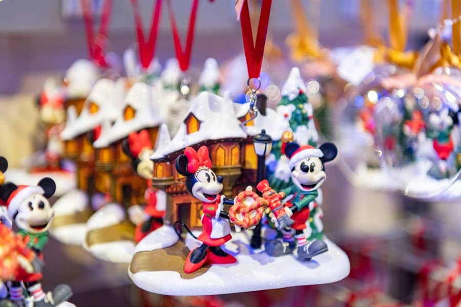 Mickey and Minnie Mouse Christmas ornaments adorned with gifts, snow, and festive Disney decorations are showcased together, capturing the magical holiday spirit guests love to experience at Disney parks and resorts.