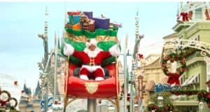 Santa Claus greets guests from a brilliantly decorated red sleigh float surrounded by gifts, gliding down Main Street U.S.A. during the magical Christmas Cavalcade at Magic Kingdom.