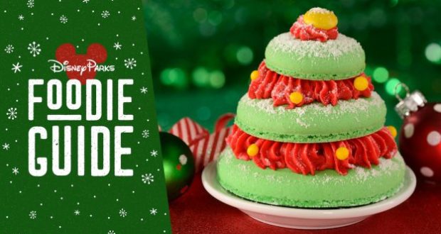 Festive green Christmas tree macaron topped with red frosting and yellow candy, showcased next to the "Disney Parks Foodie Guide"—a magical holiday treat available at Magic Kingdom for Disney fans and foodies to enjoy.