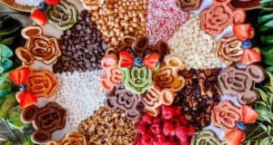 Mickey and Minnie-shaped waffles piled high on a festive board with fresh fruit, crunchy nuts, chocolate chips, and vibrant toppings—this eye-catching Disney snack platter is perfect for fans planning a magical treat inspired by their favorite characters at Walt Disney World or Disneyland.
