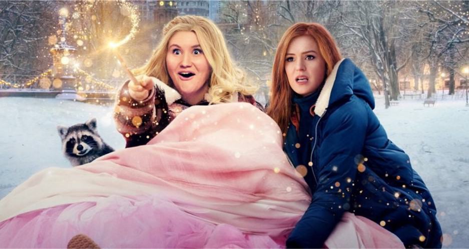 Two costumed characters from Disney+’s “Godmothered” bring winter magic to life, with one joyfully waving her wand and a raccoon character nestled in cozy blankets, surrounded by sparkling lights—capturing the whimsical spirit and movie magic theme park fans love.