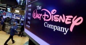 Disney Company logo displayed on a large screen at a bustling stock exchange, with excited traders and glowing monitors in the background, capturing the enthusiasm as Disney celebrates record-breaking success that has thrilled fans of its movies, theme parks, and beloved characters.