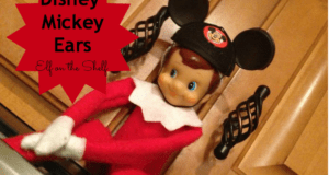 Elf on the Shelf, sporting handmade Mickey Mouse ears, is perched by the kitchen cabinets as playful text announces "Disney Mickey Ears"—bringing a bit of Disney magic into your home.