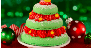 A Belle’s Enchanted Christmas Tree cookie shaped like a green Christmas tree, decorated with festive red and yellow icing, served on a plate with holiday ornaments—an enchanting treat available at Disney Parks for the holiday season.