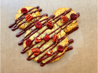 Three cookies arranged to resemble a bear’s face, finished with chocolate drizzle, nuts, and dried berries on a festive mat—a whimsical Disney-inspired snack perfect for fans of DisneyMagicMoments.