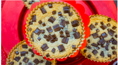 Chocolate chip muffins in vibrant red cupcake liners on a bright red plate, seen from above—reminiscent of classic theme park treats and perfect for celebrating National Cookie Day with Disney-inspired flair.
