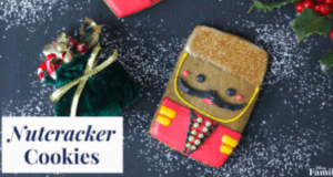 A whimsical Nutcracker-shaped cookie with a dapper mustache stands proudly next to a festive green gift box and sprigs of holly on a sugar-sprinkled surface—these Nutcracker cookies capture the enchanting spirit of holiday parades and themed celebrations, bringing that signature touch of magic to your festive treat lineup.
