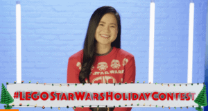 A Star Wars fan beams in a themed sweater against a vibrant blue backdrop, with the #LEGOSTARWARSHOLIDAYCONTEST banner below, ready to dive into the festive LEGO Holiday Contest excitement.