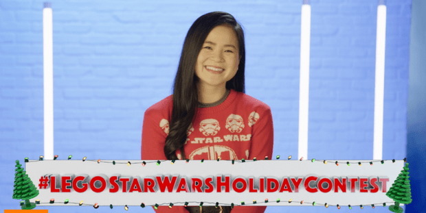 A Star Wars fan beams in a themed sweater against a vibrant blue backdrop, with the #LEGOSTARWARSHOLIDAYCONTEST banner below, ready to dive into the festive LEGO Holiday Contest excitement.