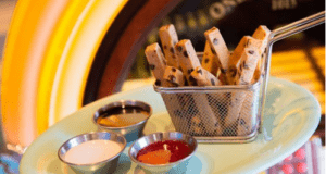 At Disney’s Beaches & Cream Soda Shop, Mickey Plant-Based Cookie Fries bring the fun with chocolate chip cookie sticks shaped like fries, served in a playful basket alongside three tasty dipping sauces—perfect for park guests looking for a delicious plant-based treat.
