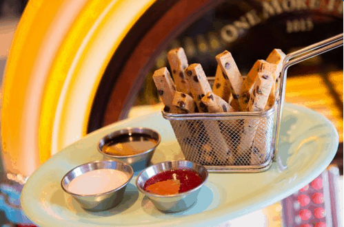 At Disney’s Beaches & Cream Soda Shop, Mickey Plant-Based Cookie Fries bring the fun with chocolate chip cookie sticks shaped like fries, served in a playful basket alongside three tasty dipping sauces—perfect for park guests looking for a delicious plant-based treat.