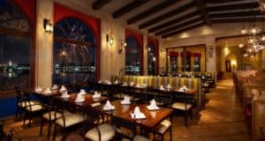 La Hacienda de San Angel at EPCOT creates an unforgettable atmosphere with its stylish set tables, striped booths, and panoramic windows overlooking the World Showcase Lagoon—offering spectacular views of nighttime fireworks for Disney fans savoring one of the park’s most enchanting dining experiences, especially as it approaches its final nights.