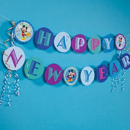 Two vibrant banners emblazoned with "Happy New Year," featuring Mickey Mouse graphics and shimmering silver curly ribbons, decorate a blue backdrop—capturing the excitement of a Disney-themed New Year's celebration that brings a magical park atmosphere to any setting.