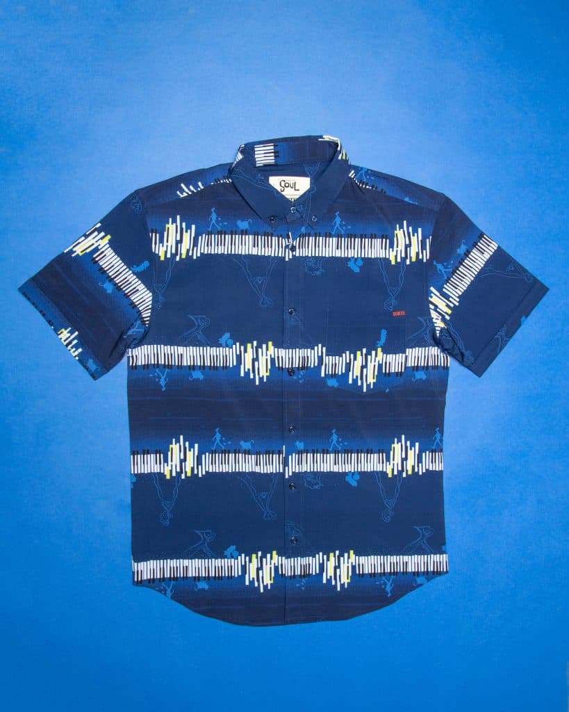 Navy short-sleeve button-up shirt featuring bold white and yellow geometric stripes, displayed on a blue backdrop as part of the exclusive Disney Soul merchandise collection available at Disney parks and resorts.