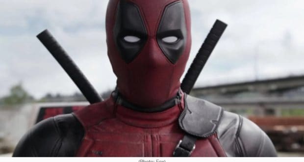 Deadpool, in his signature red and black mask with two swords strapped to his back, poses outdoors, capturing the iconic vibe fans anticipate for Deadpool 3 as Disney gears up for its R-rated blockbuster.