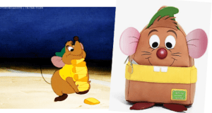 Gus Gus from Cinderella eagerly stacks cheese next to a Cinderella Loungefly Backpack featuring his signature big ears and green hat, perfect for Disney fans at the parks.