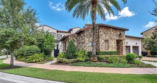 A grand Disney Resort Home featuring elegant stone and stucco architecture, a tall palm tree, neatly trimmed shrubs, and a picturesque blue sky dotted with clouds—this magical property near the enchantment of Walt Disney World recently sold for $2.4 million.