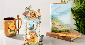 Winnie the Pooh mug, themed hourglass, collectible card, storybook, and pencil displayed on a table with lush greenery in the background—perfect for fans of Disney's Hundred Acre Wood experience.