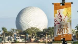 Festival of the Arts 2021 banner set against Epcot's iconic Spaceship Earth, showcasing the colorful excitement and creative energy at Disney EPCOT International Festival of the Arts.