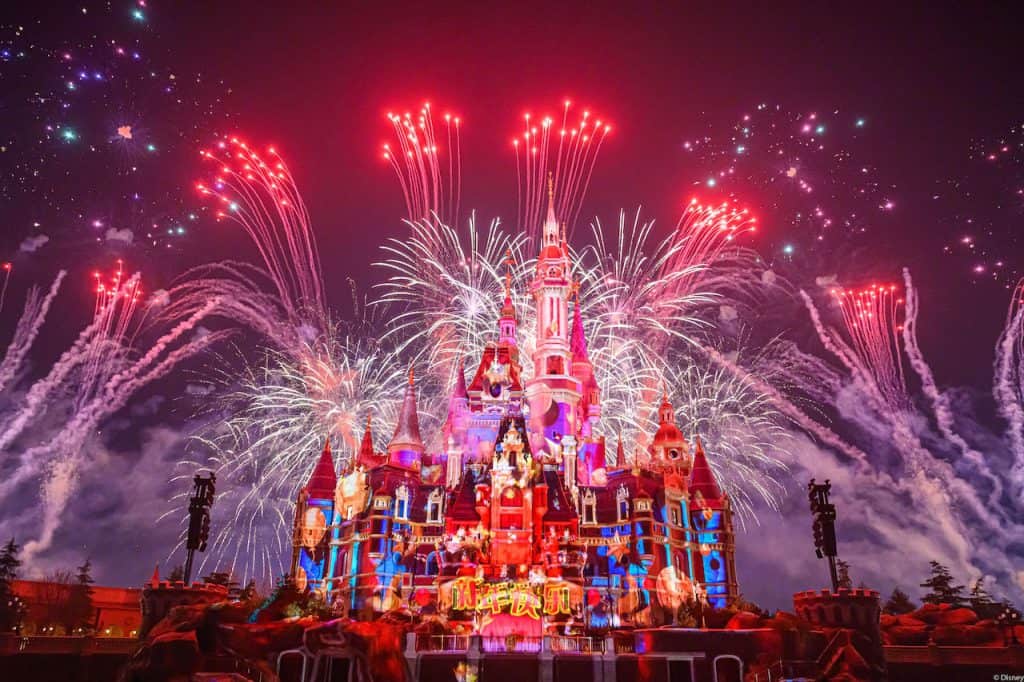 Shanghai Disneyland’s Enchanted Storybook Castle glows against the night sky as vibrant fireworks explode overhead, marking the park’s spectacular Fifth Anniversary celebration.