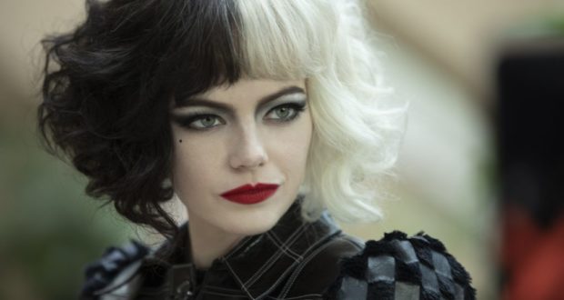 Cruella De Vil, with her signature black and white hair, dramatic makeup, and bold checkered jacket, glances to the side in a look straight from the first Cruella movie trailer—a striking representation of her rebellious Disney Villains style perfect for character meet-and-greets or themed entertainment events.