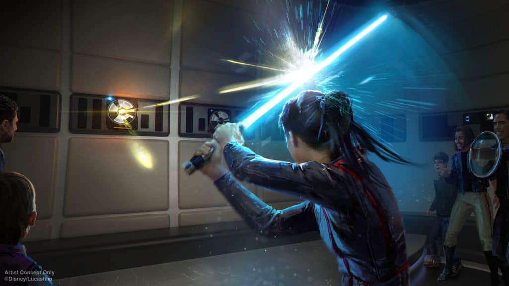 A Star Wars: Galactic Starcruiser guest wields a blue lightsaber to deflect laser blasts during an interactive onboard experience, as fellow travelers look on in excitement.