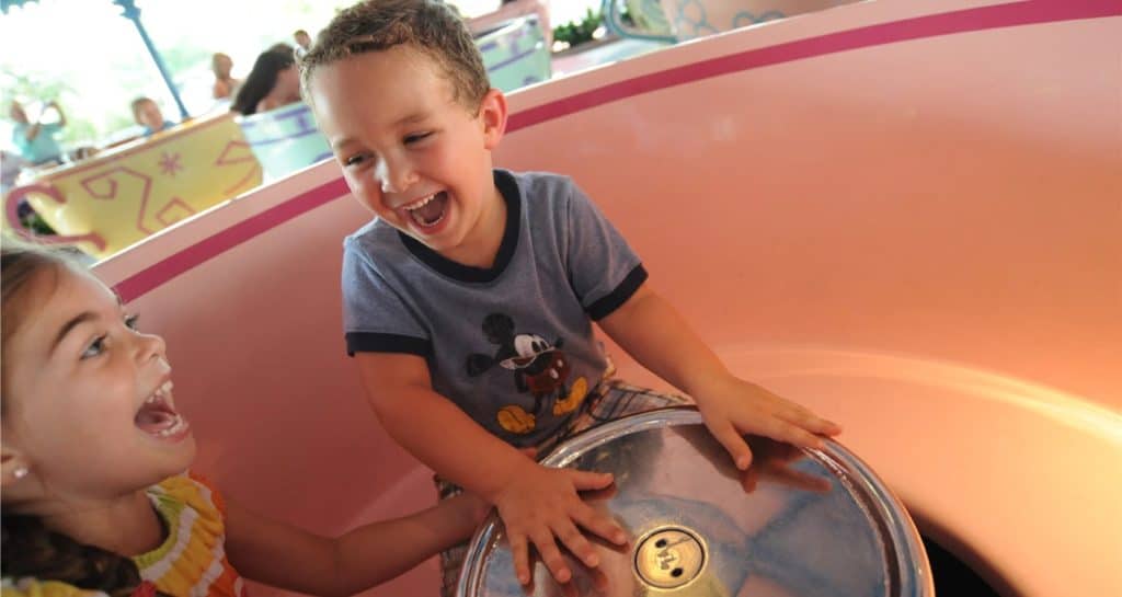 Guests delight as two children share laughter, spinning together in a colorful teacup on the iconic Mad Tea Party ride in Magic Kingdom.