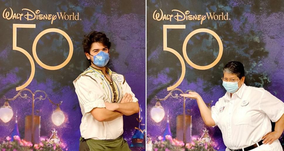 Disney Cast Members sporting masks strike a fun pose in front of the shimmering Walt Disney World 50th Anniversary celebration backdrop.