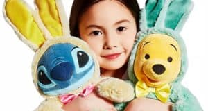 A young Disney fan embraces plush Stitch and Winnie the Pooh, who are both dressed in vibrant Easter Bunny costumes, ready for springtime festivities at a Disney park.