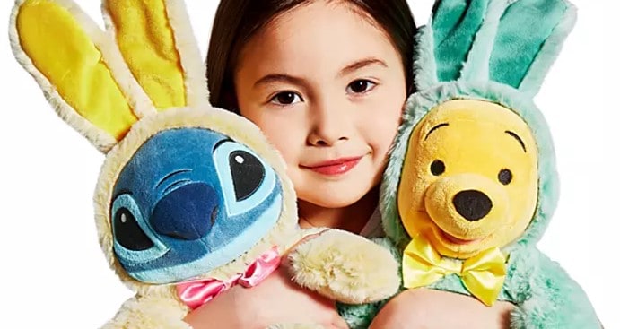 A young Disney fan embraces plush Stitch and Winnie the Pooh, who are both dressed in vibrant Easter Bunny costumes, ready for springtime festivities at a Disney park.