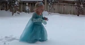 Elsa, wearing her sparkling tiara and signature dress, enjoys a magical moment in the snow by a wooden fence—straight out of "Let It Go," ready for her next adventure at Arendelle.